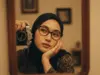 Hasil edit foto AI pose memegang kamera vintage