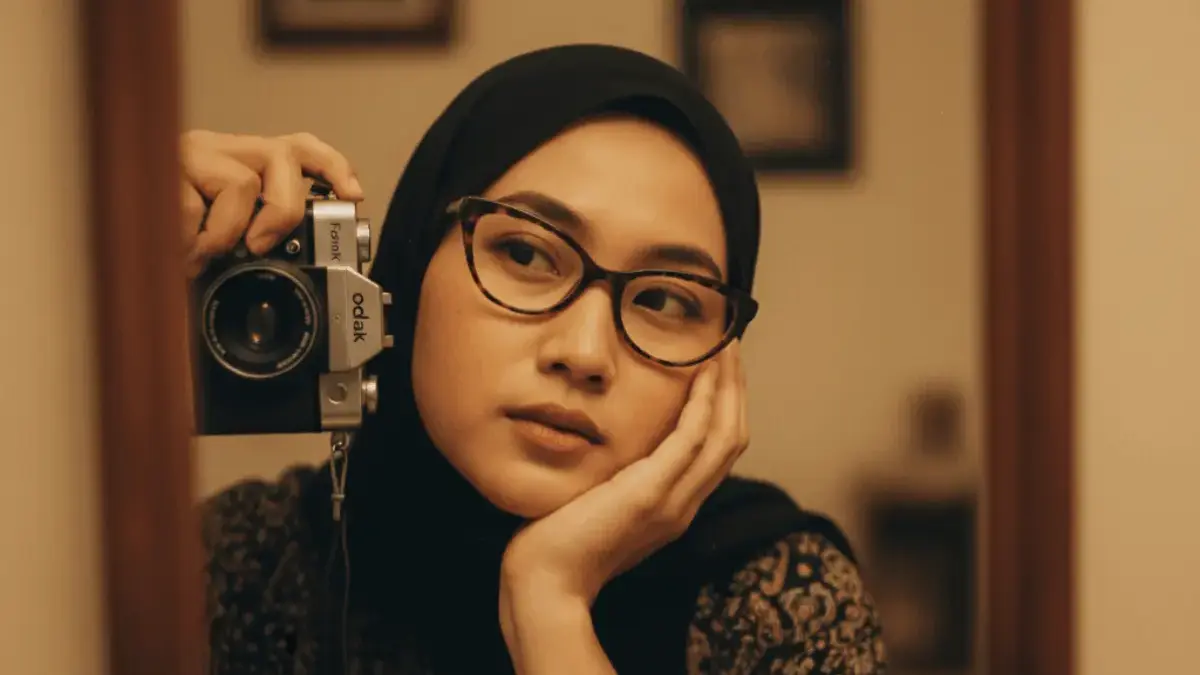 Hasil edit foto AI pose memegang kamera vintage